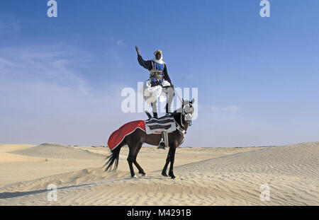 La Tunisie. Oasis de Douz. Désert du Sahara. Homme debout sur le cheval, dans la région de dunes de sable, habillé pour festival. Banque D'Images