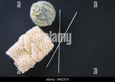 Une balle de laine avec des aiguilles à tricoter et de chaussettes sur un tableau gris. La couture Banque D'Images