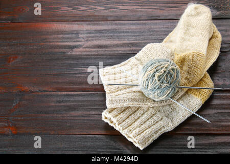 Une balle de laine avec des aiguilles à tricoter chaussettes tricotées et sur une table en bois. La couture Banque D'Images
