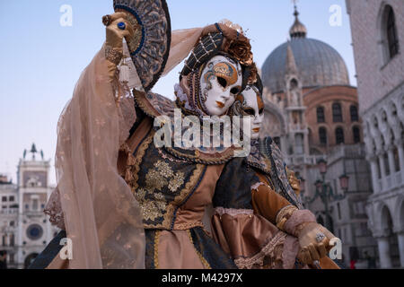 Deux femmes en costume traditionnel et masques peints, décorés avec des fans, debout en face du Palais des Doges durant la Carnaval de Venise Banque D'Images