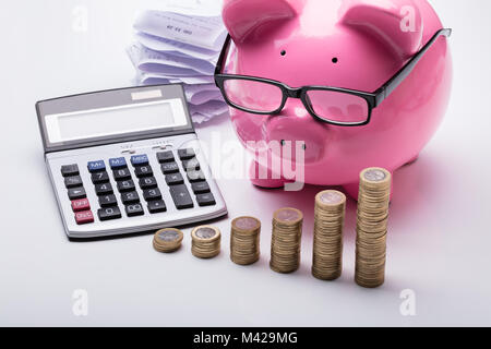 Close-up de pièces empilées avec Tirelire et Calculatrice sur 24 Banque D'Images