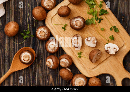 Planche à découper, champignons tranchés, couteau et serviette sur une toile de fond en bois brun. Vue d'en haut Banque D'Images