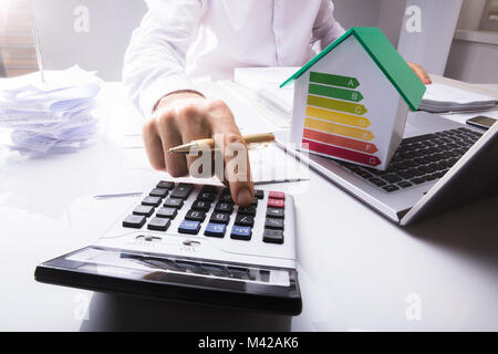 Le calcul des données financières d'affaires avec maison modèle sur ordinateur portable montrant le taux d'efficacité énergétique In Office Banque D'Images