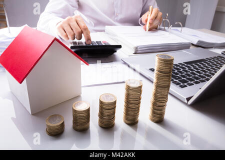 Businessman Calcul Calculatrice avec l'aide de factures et modèle de maison pile de pièces sur 24 Banque D'Images