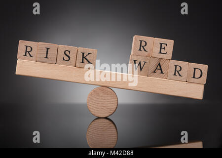 Close-up d'une balançoire en bois montrant déséquilibre entre le risque et la rémunération sur fond gris Banque D'Images