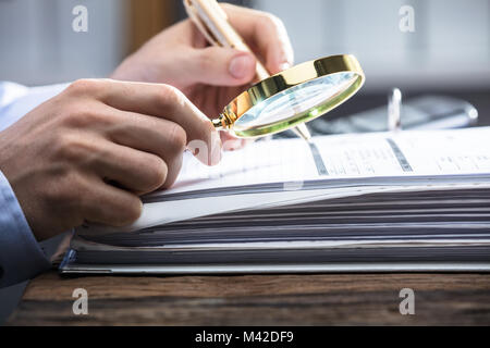 Close-up de l'homme d'affaires à la main à la loupe par facture Banque D'Images