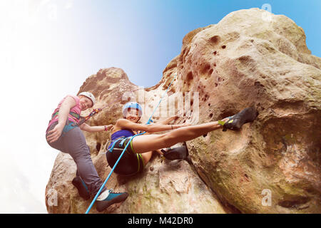 Fond Voir portrait de femme instructeur adolescente escalade un rocher avec les faisceaux contre le ciel bleu Banque D'Images