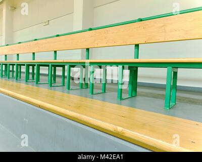 Des rangées de bancs en bois vides à l'école de sport. Tribune dans une salle de sport pour les fans de matchs avec sièges en bois vide. Banque D'Images