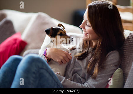 Jeune femme avec chiot à la maison Banque D'Images