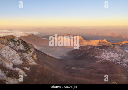 Vue au-dessus des nuages de la montagne de la vallée de l'échelle de Lovcen et des pics de montagne au coucher du soleil. Banque D'Images