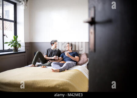 Jeune homme couple de détente avec petit-déjeuner au lit Banque D'Images