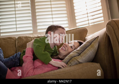 Mère Fils de chatouillement sur canapé Banque D'Images