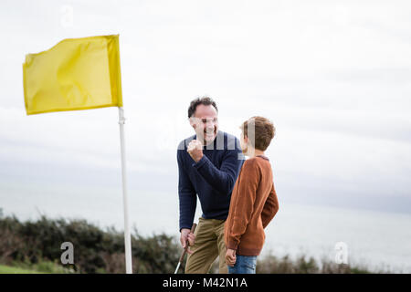 Père de célébrer avec son on golf course Banque D'Images