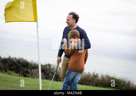 Père hugging son on golf course Banque D'Images