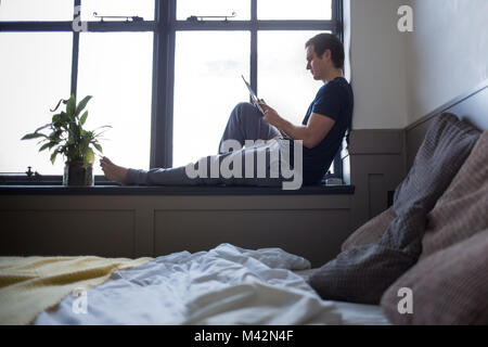 Jeune homme la lecture sur tablette numérique Banque D'Images