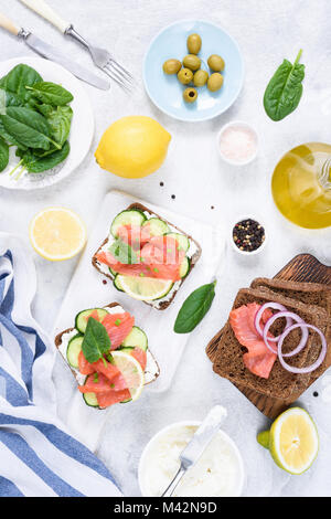Sandwichs toasts avec du saumon, crème de fromage, olives et de concombre sur tableau blanc. Vue d'en haut. Table à dîner Banque D'Images
