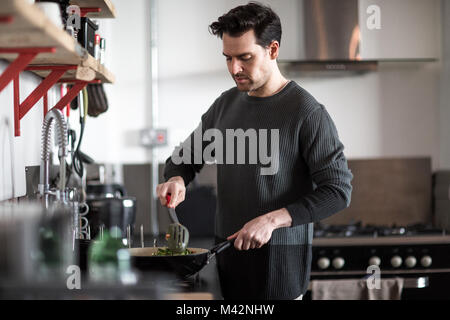 Jeune homme cooking in kitchen Banque D'Images