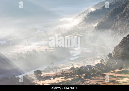 Punakha, Bhoutan. Soleil du matin illumine brume du matin dans la vallée de la rivière Mo. Banque D'Images