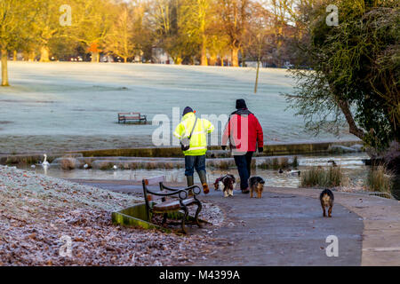 Northampton, Royaume-Uni 14 février 2018. Météo. Une lumineuse froide pour commencer la journée avec une forte gelée, Dog Walkers enveloppé contre le froid l'exercice de leurs animaux à Abington Park, la prévision est pour la pluie plus tard dans la journée. Credit : Keith J Smith./Alamy Live News Banque D'Images