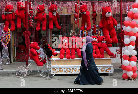 La ville de Gaza, bande de Gaza, territoire palestinien. Feb 14, 2018. Une femme palestinienne passe devant une boutique qui vend des ours en peluche rouge, ballons rouges et oreillers le jour de la saint Valentin dans la ville de Gaza le 14 février 2018. La Saint Valentin est de plus en plus populaires dans la région car les gens ont pris la coutume de donner des fleurs, des chocolats, des cartes et des cadeaux pour amoureux pour célébrer l'occasion Crédit : Ashraf Amra/APA/Images/fil ZUMA Alamy Live News Banque D'Images