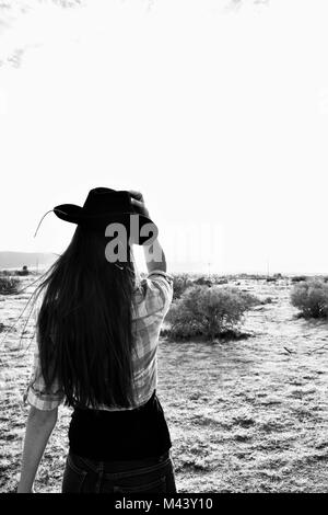 Country Girl In Desert Holding Hat noir et blanc Banque D'Images