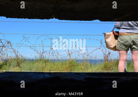 Vue de l'intérieur allemand bunker défensives sur falaise à Omaha Beach, Normandie à fil et bardé de touristes à la recherche D-Day landing site Banque D'Images