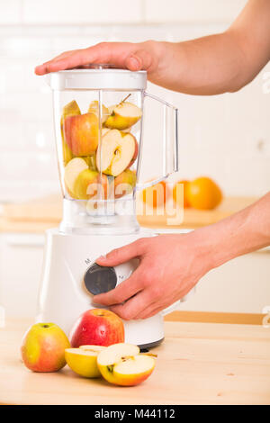 Blender blanc avec pommes sur une table en bois. Banque D'Images