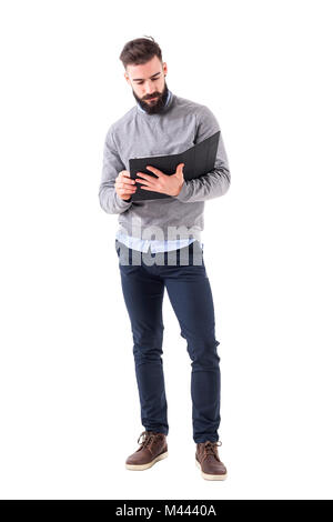 Élégant barbu sérieux teacher holding et la lecture de l'ordinateur portable. La pleine longueur du corps portrait isolé sur fond blanc studio. Banque D'Images