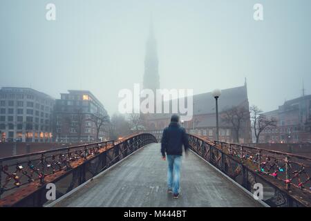 L'homme est la marche sur le pont de fer à l'église de brouillard mystérieux. Hambourg, Allemagne. Banque D'Images