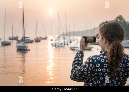 Rear view of woman photographing bateaux au coucher du soleil, Lazise, Vénétie, Italie, Europe Banque D'Images