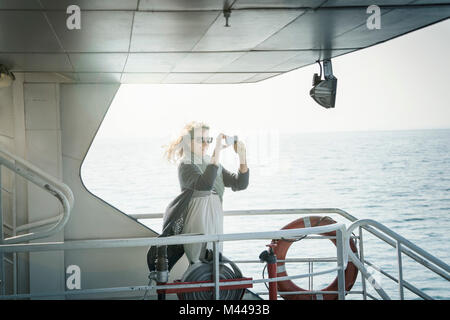 Femme sur ferry taking photograph Banque D'Images