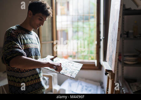 L'application de la peinture à l'huile de l'artiste masculin à la palette en studio des artistes Banque D'Images