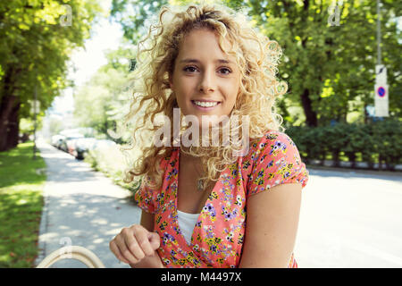 Portrait de curly haired blonde woman smiling at camera Banque D'Images