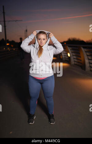 Portrait de jeune femme plantureuse, obtenir de la formation sur la passerelle à capuche prêt nuit Banque D'Images