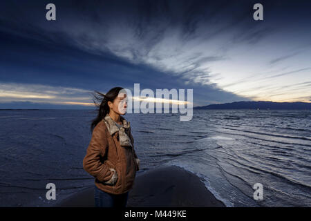 Young woman gazing sur plage de vent au crépuscule, Tarragone, Catalogne, Espagne Banque D'Images