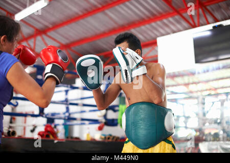 Young woman laying on boxe avec male trainer in gym Banque D'Images