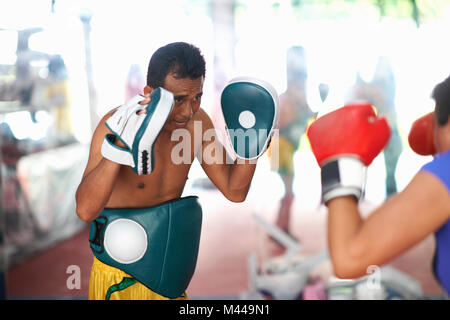 Young woman laying on boxe avec male trainer in gym Banque D'Images