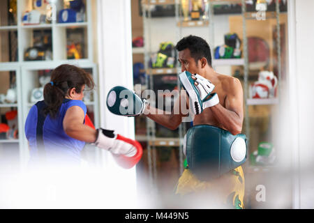 Young woman laying on boxe avec male trainer in gym Banque D'Images