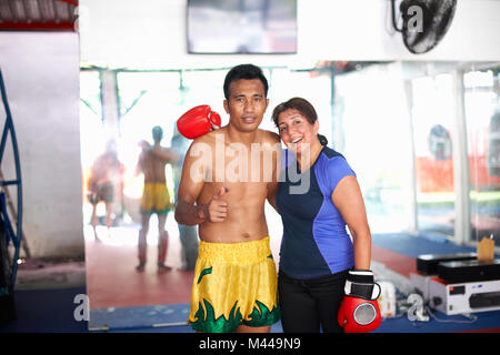 Portrait of young woman with boxing trainer in gym Banque D'Images