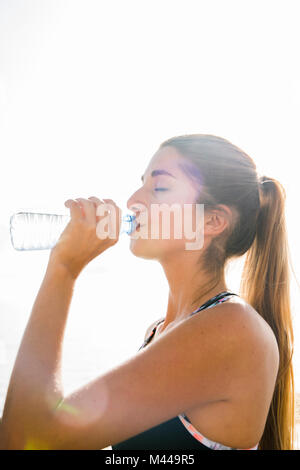 Jeune femme de la formation, de l'eau en bouteille de boisson Banque D'Images