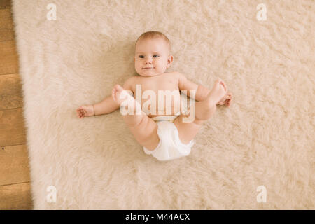 Portrait de frais généraux de cute baby girl lying on couche en tapis beige Banque D'Images