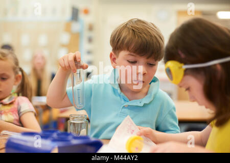 Primary schoolboy et filles faisant test tube experiment in classroom Banque D'Images