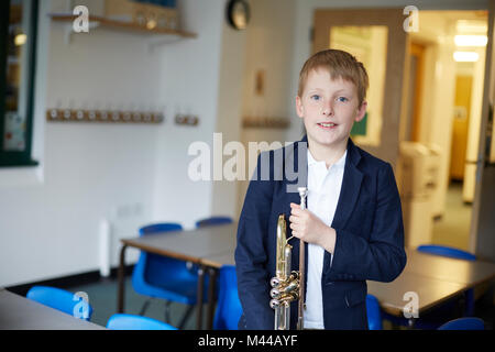 Primary schoolboy holding Trumpet in classroom, portrait Banque D'Images