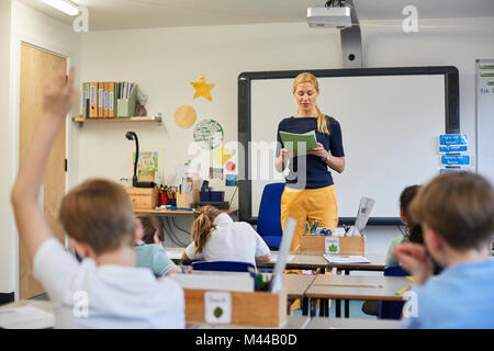 Avec la main d'écolier soulevées dans la leçon en classe à l'école primaire Banque D'Images