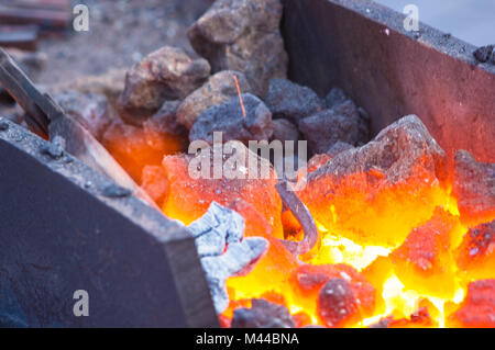 Four de forge avec des charbons, des outils et des pièces de métal chaud rougeoyant, close-up Banque D'Images