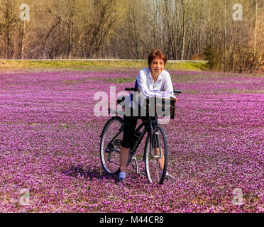 Les femmes plus âgées est un cycliste dans le champ de fleurs sauvages s'appuyant sur son vélo et souriant ; printemps dans le Missouri, Midwest Banque D'Images