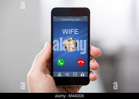 Close-up of a Hand Holding Smart Phone avec femme Appel entrant sur l'affichage Banque D'Images