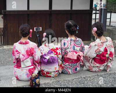 Vue de derrière d'un groupe de quatre touristes fille chinois vêtus de kimonos loué selfies posant pour une Banque D'Images