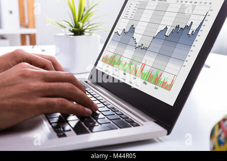 Close-up d'un courtier en bourse Analyse graphique de la main On Laptop In Office Banque D'Images