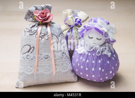 Pochette et sachets parfumés la figure d'une jeune fille. Close up de sacs remplis de lavande sur table en bois ou un conseil. La décoration. Banque D'Images